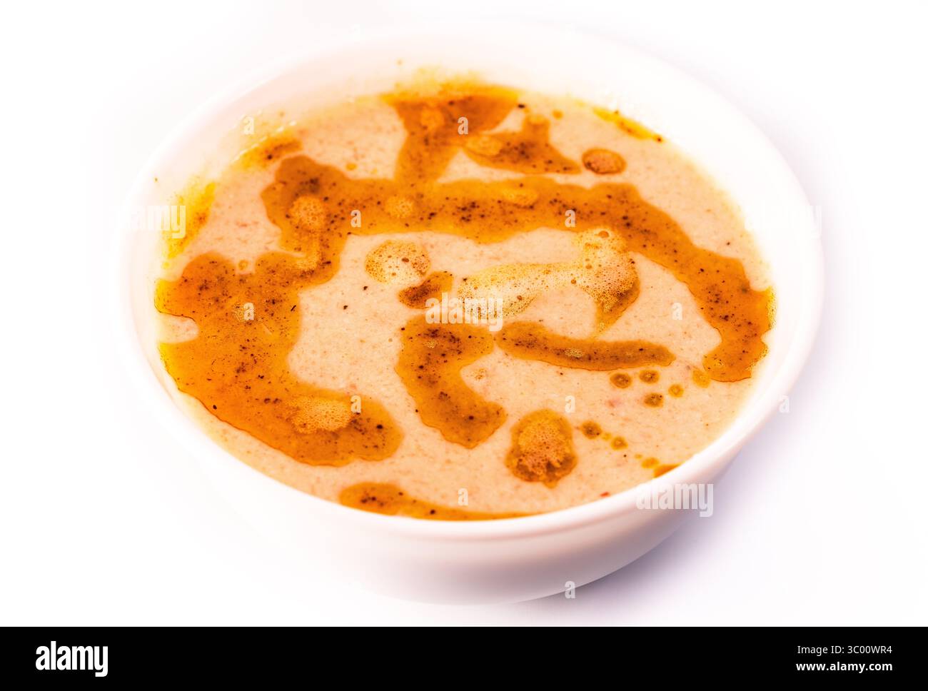 Geschmeidige Buttersuppe, abgerundet mit einem Band aus goldener geklärter Butter und zartem Schaum in einer minimalistischen weißen Schüssel Stockfoto