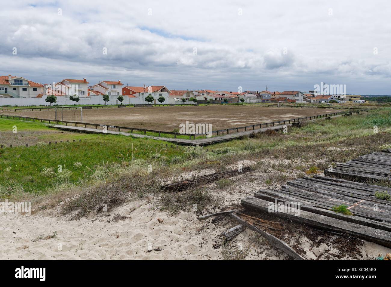 Verlassenes Fußballfeld, das sich in die Küstenlandschaft in der Nähe von Wohnhäusern in Figueira da Foz einfügt Stockfoto