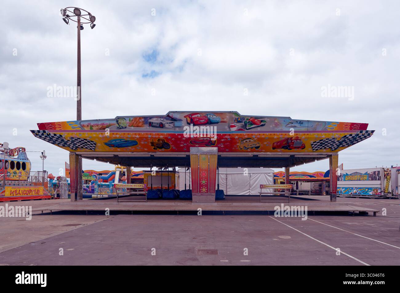 Frontansicht auf den bunten Pavillon mit Auto-Cartoons, dekoriert mit Cartoon-Rennfahrern auf einem leeren Messegelände Stockfoto