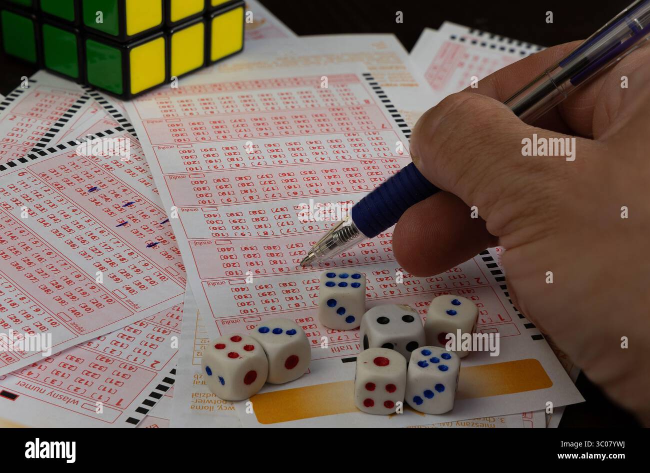 Das Ausstreichen von Glückszahlen in einer großen Geldverlosung, ein Lottoticket, das Markieren von Zahlen mit einem Stift auf einem Spielschein Stockfoto