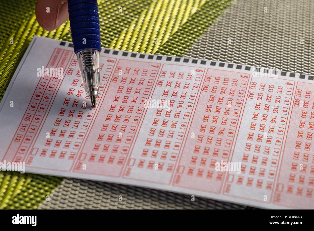 Das Ausstreichen von Glückszahlen in einer großen Geldverlosung, ein Lottoticket, das Markieren von Zahlen mit einem Stift auf einem Spielschein Stockfoto