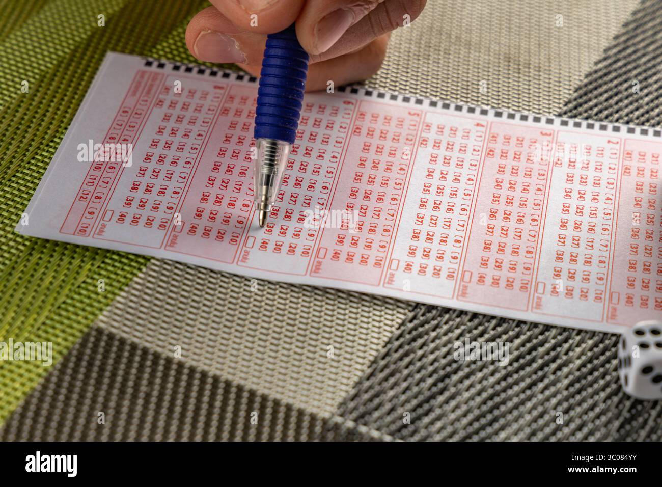 Das Ausstreichen von Glückszahlen in einer großen Geldverlosung, ein Lottoticket, das Markieren von Zahlen mit einem Stift auf einem Spielschein Stockfoto