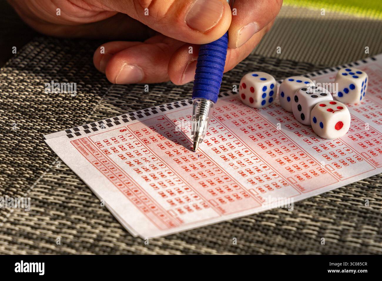 Das Ausstreichen von Glückszahlen in einer großen Geldverlosung, ein Lottoticket, das Markieren von Zahlen mit einem Stift auf einem Spielschein Stockfoto