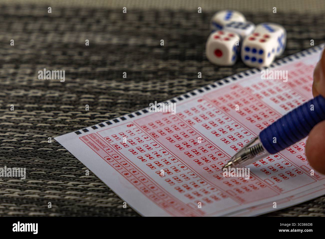 Das Ausstreichen von Glückszahlen in einer großen Geldverlosung, ein Lottoticket, das Markieren von Zahlen mit einem Stift auf einem Spielschein Stockfoto