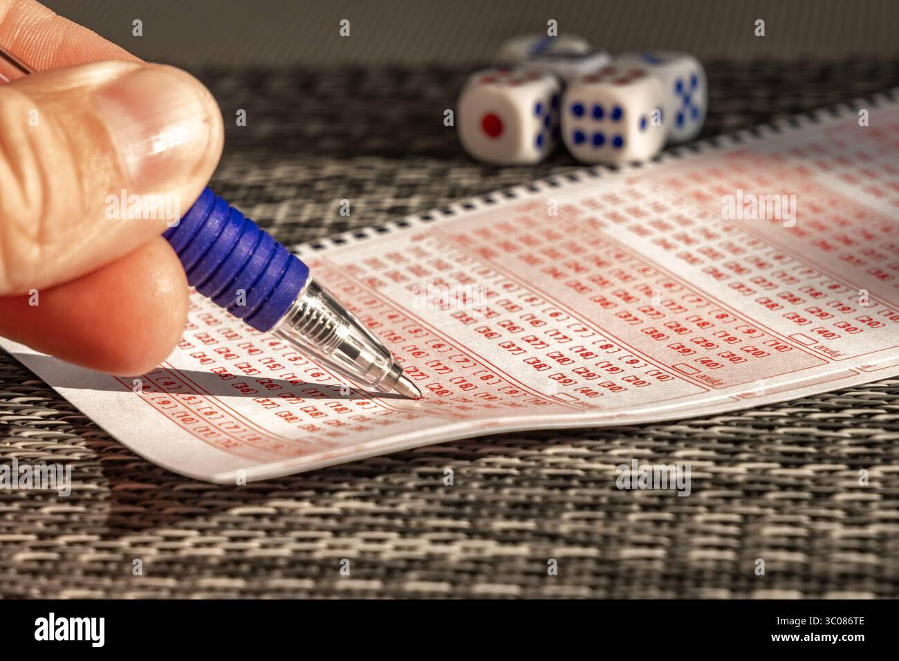 Das Ausstreichen von Glückszahlen in einer großen Geldverlosung, ein Lottoticket, das Markieren von Zahlen mit einem Stift auf einem Spielschein Stockfoto