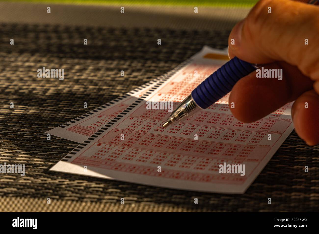 Das Ausstreichen von Glückszahlen in einer großen Geldverlosung, ein Lottoticket, das Markieren von Zahlen mit einem Stift auf einem Spielschein Stockfoto