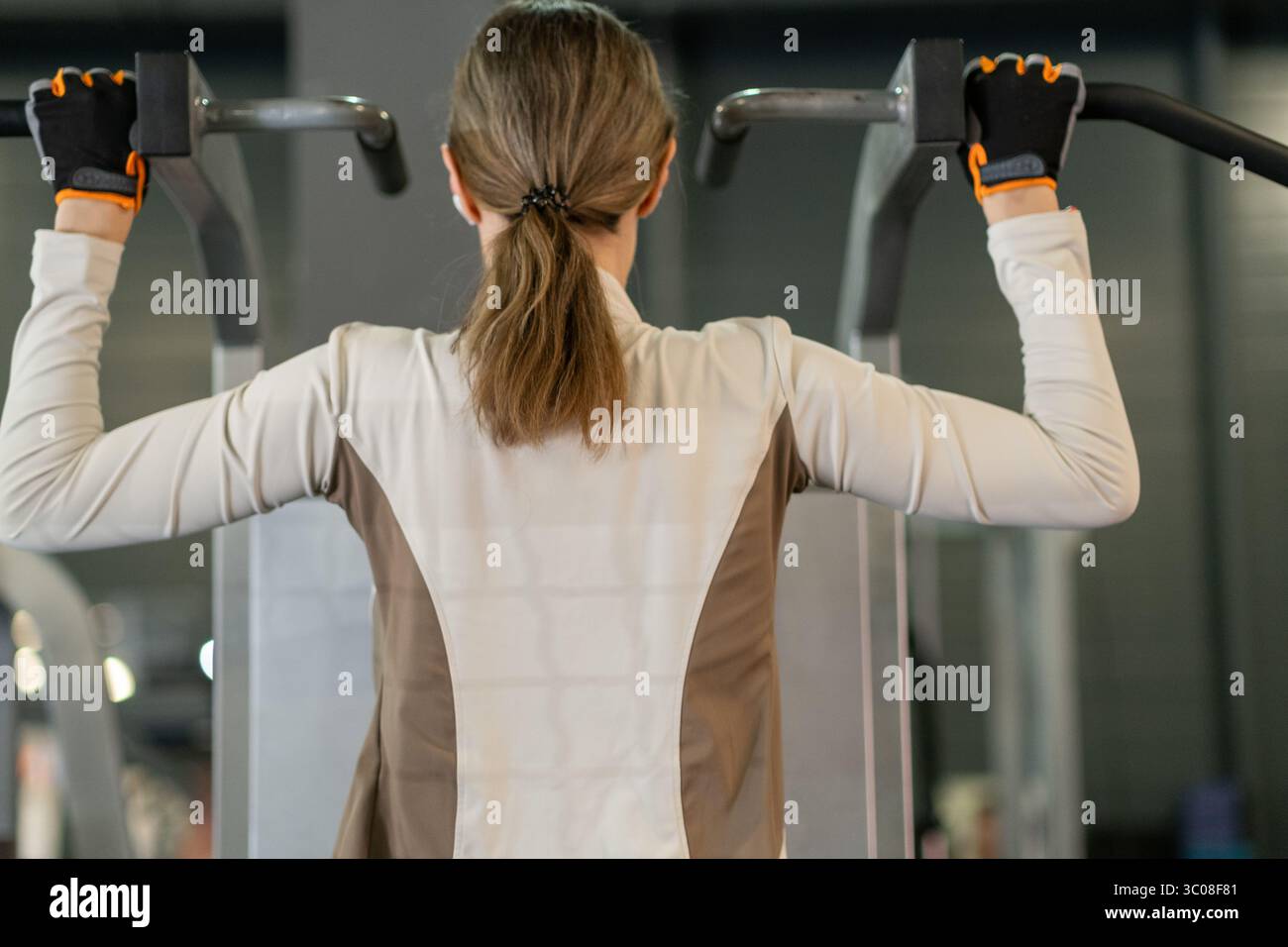 In einem modernen Indoor Gym führt die Person Klimmzüge durch und arbeitet in einer strukturierten Trainingsroutine an Oberkörperkraft und Ausdauer. Stockfoto