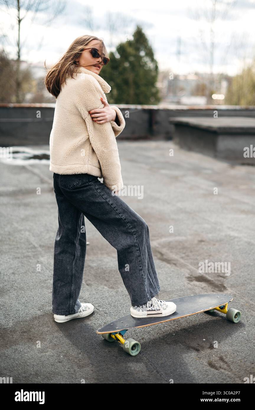 Selbstbewusste junge Posen mit Skateboard auf dem Dach Stockfoto