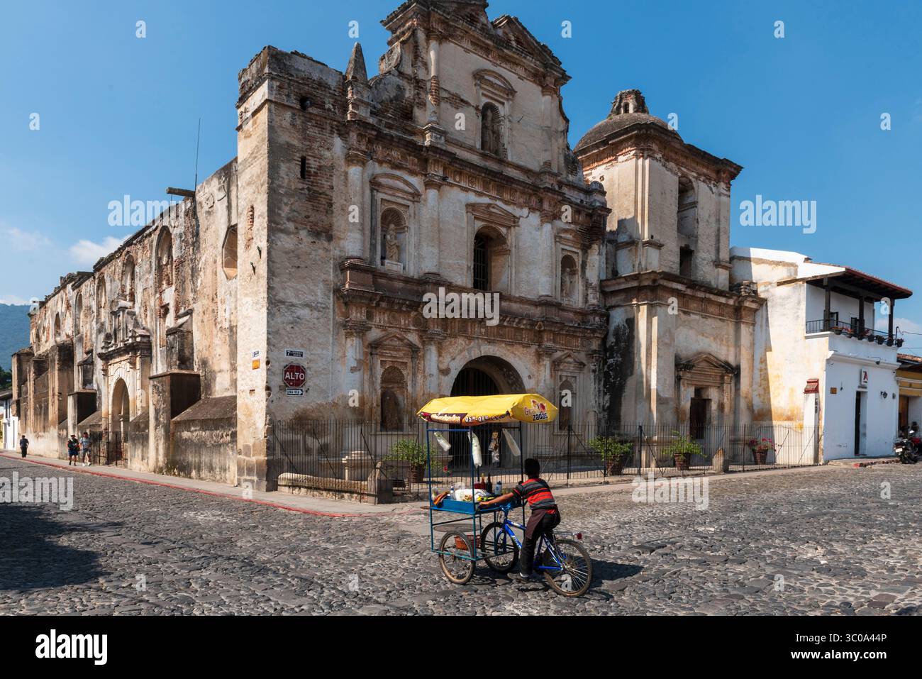 Eine Person, die ein Dreirad vor der Kirche San Agustin fährt Stockfoto Eine Person, die ein Dreirad vor der Kirche San Agustin fährt Stockfoto