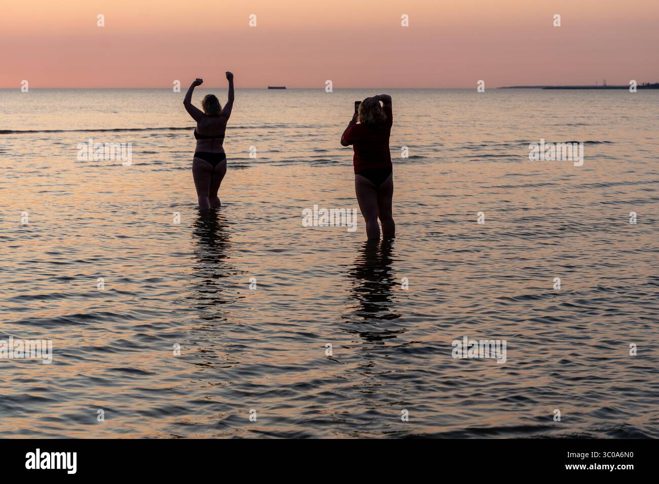 Reife Frau posiert selbstbewusst am Pirita Beach bei Sonnenuntergang Stockfoto