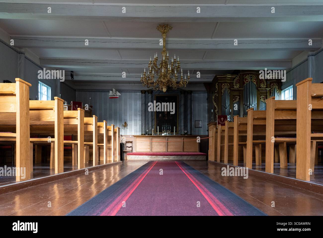 Innenraum der Käsmu-Kirche in Estland, Holzbänke, roter Teppichgang, Altar, Kronleuchter – historische sakrale Architektur der Ostsee und friedliche Atmosphäre Stockfoto