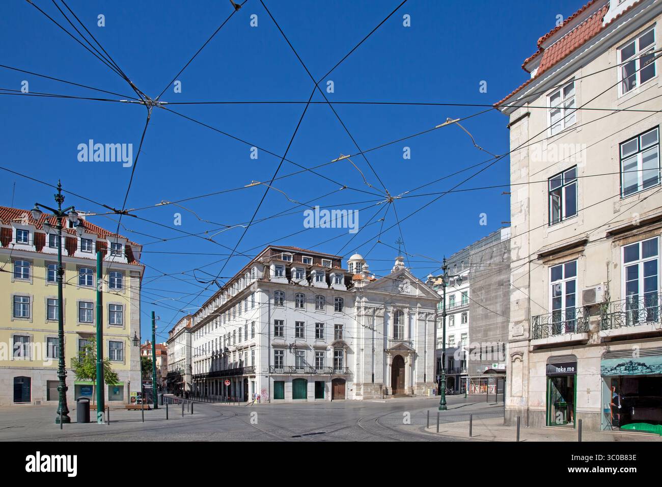 Alte Kirche am Praca do Municipio Lissabon, umgeben von klassischen Gebäuden und Straßenbahnleitungen Stockfoto