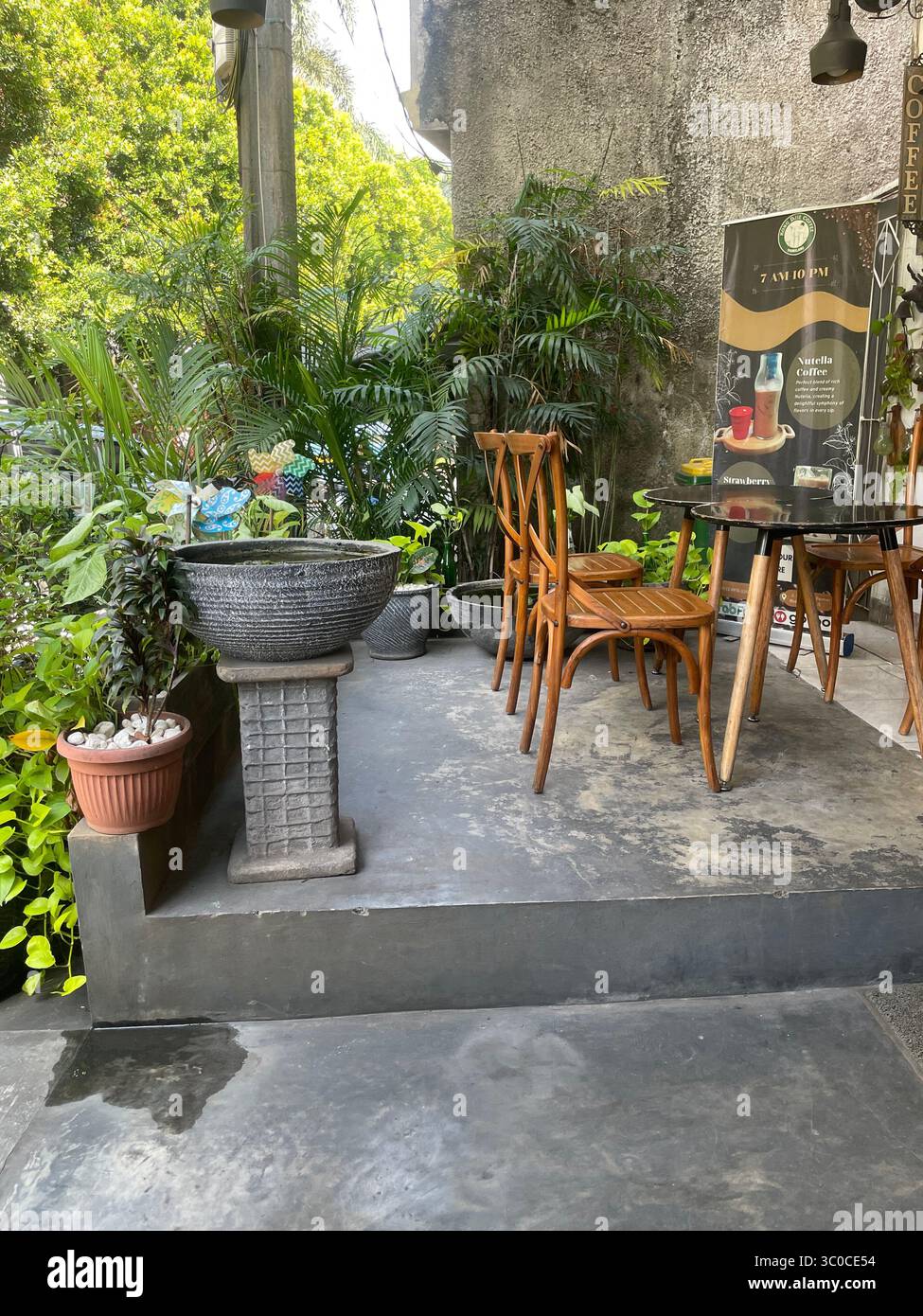 Gemütlicher Außencafé-Sitzbereich mit rustikalen Holzstühlen und -Tischen in einem Café in Tangsel Indonesien am 19. Juli 2025 - Smartphone-aufgenommenes Stockfoto