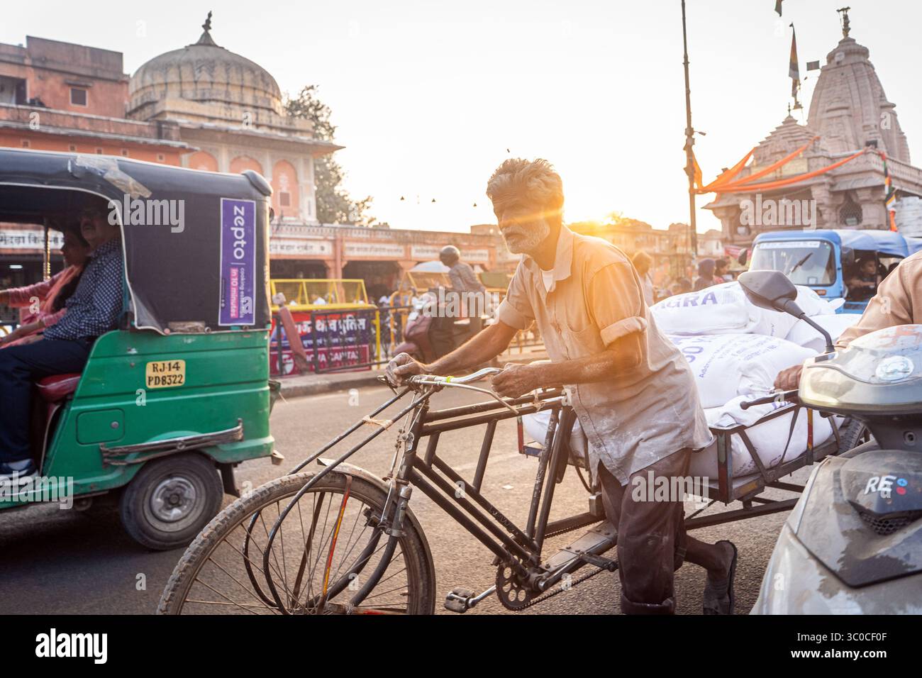 Rajasthan, Jaipur, Indien - ein Mann bei Sonnenuntergang, der eine Fahrrad-Rikscha beladen hat Stockfoto
