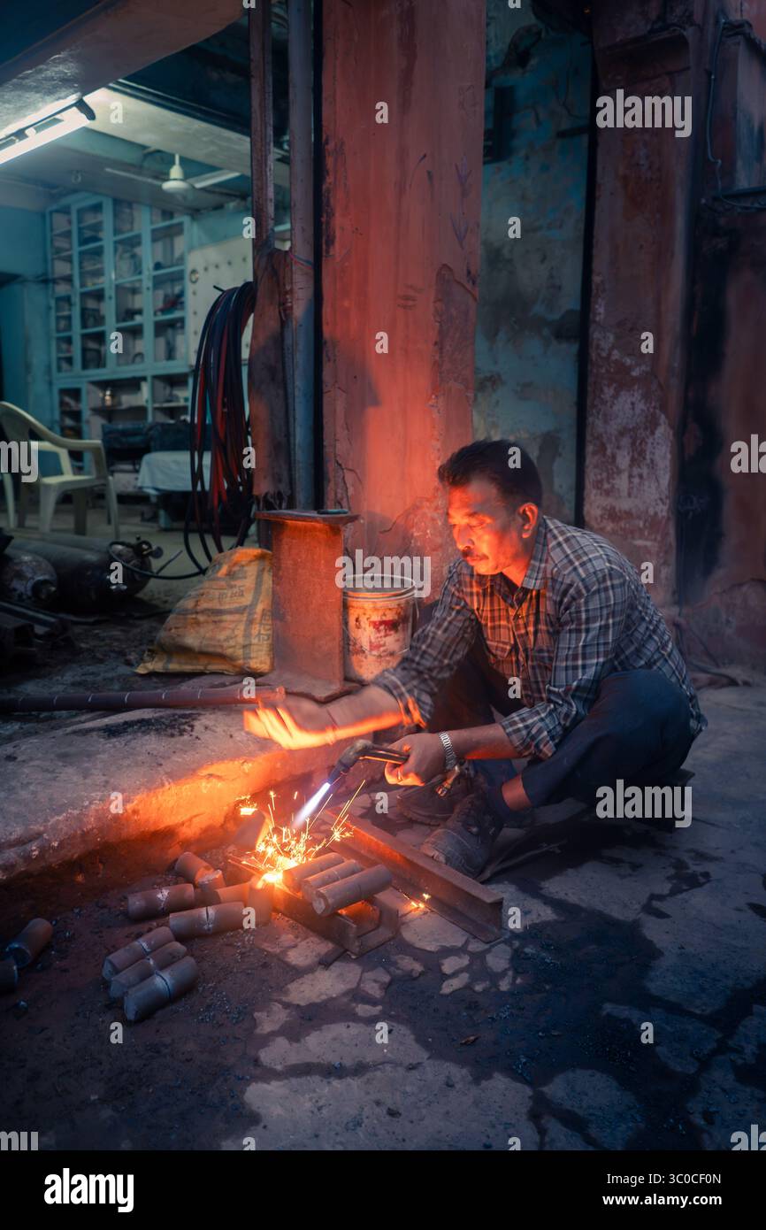 Rajasthan, Jaipur, Indien – Funken fliegen, während ein Schweißer Metall und Feuer formt – ein roher Moment der Kraft, Geschicklichkeit und Präzision auf der Straße Stockfoto