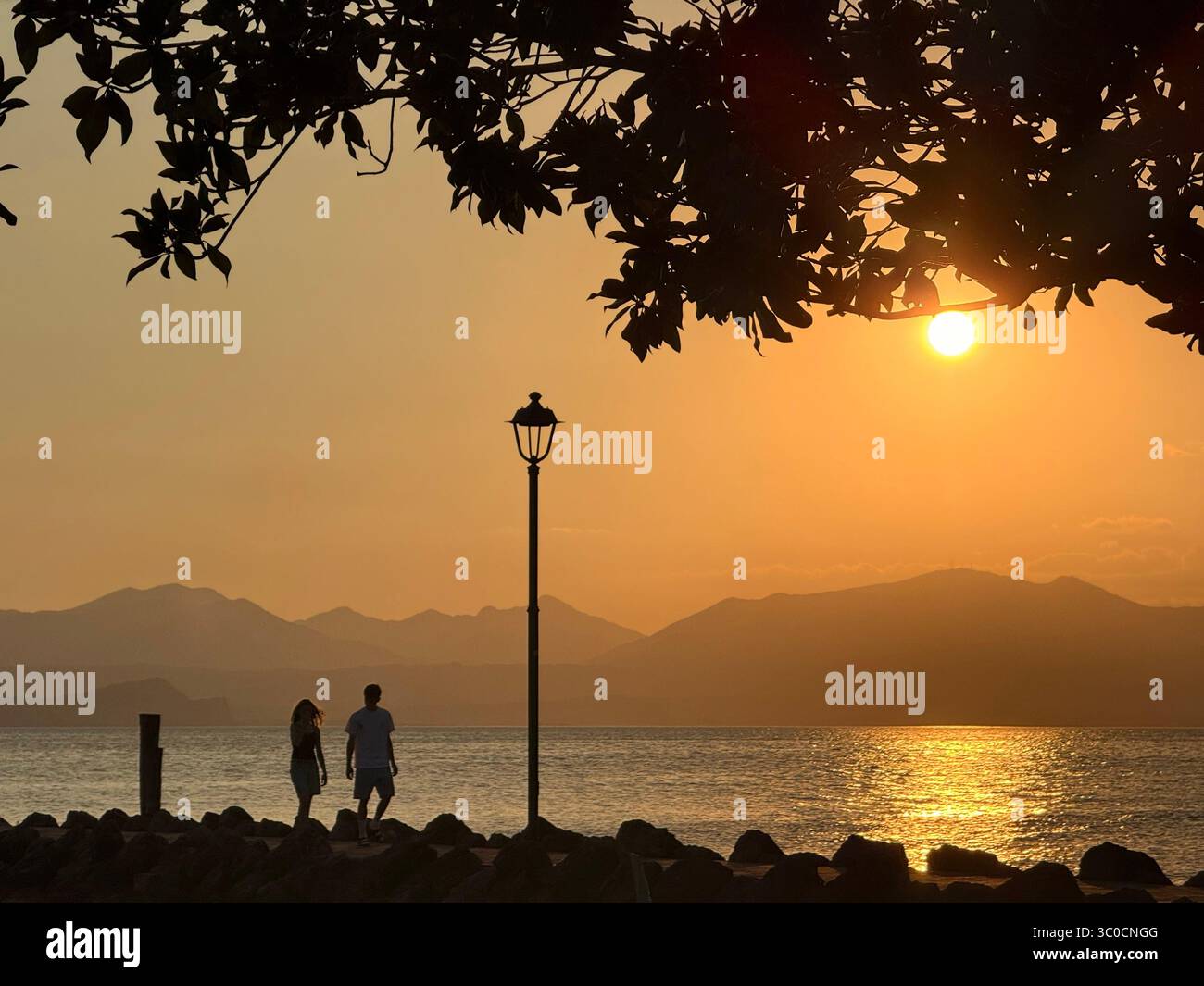 Zwei Personen bei Sonnenuntergang auf dem Steg in Cisano (bei Bardolino) am Gardasee, Italien Stockfoto