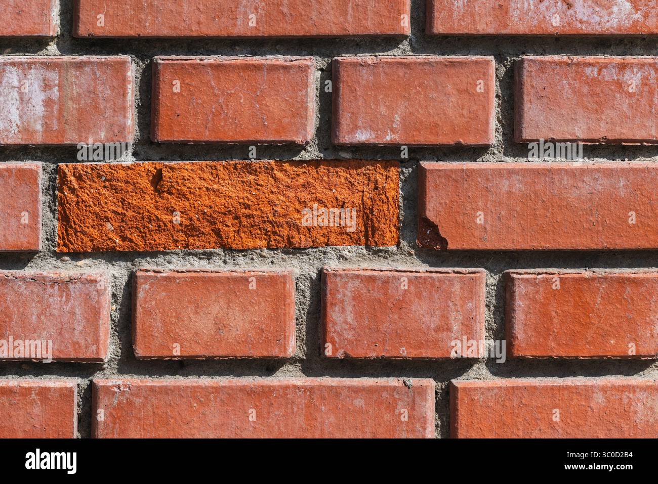 Detaillierte Nahaufnahme einer Ziegeloberfläche mit gleichmäßigen Ziegeln und einem außergewöhnlichen Ziegelstein mit rauer Textur. Hervorragend zur Illustration von Konstrukten Stockfoto