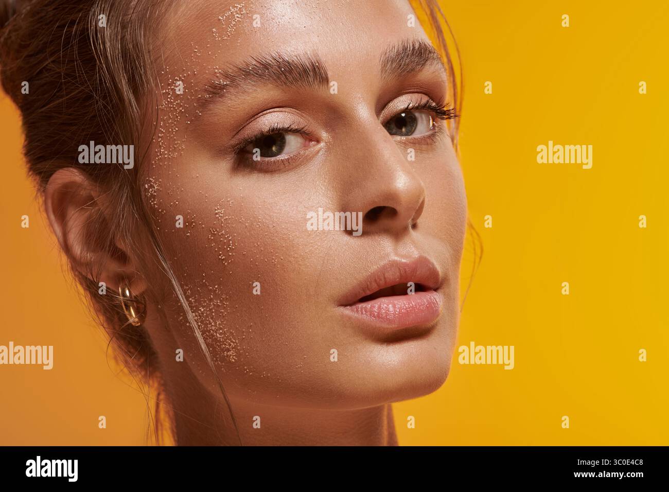 Eine junge Frau mit brauner Haut zeigt in einem warmen Studio im Sommer gebräunte Haut. Stockfoto