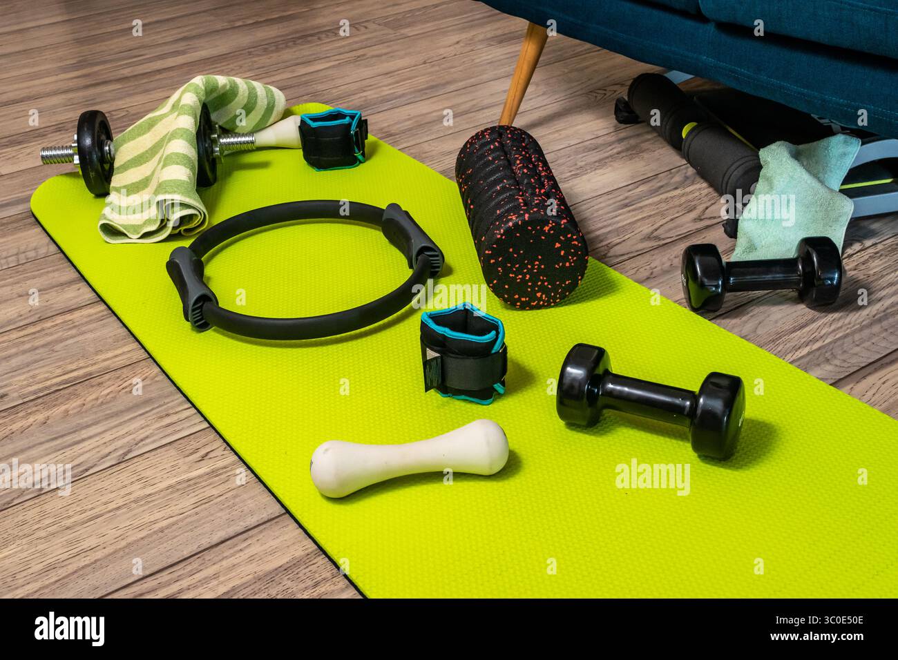 Gruppe verschiedener Trainingsgeräte auf weißem Boden des Fitnessstudios. Runde Schaumstoffrolle, Pilates Ring, Kurzhanteln, Yogamatte. FIT Lifestyle-Konzept. Stockfoto