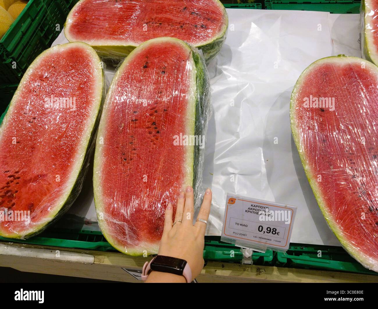 Heraklion, Kreta, Griechenland – 20. August 2024: Große halbe Wassermelonen von Akrotiri im Supermarkt erhältlich, 0,98 €/kg, handgezeichnet für Skala. Stockfoto