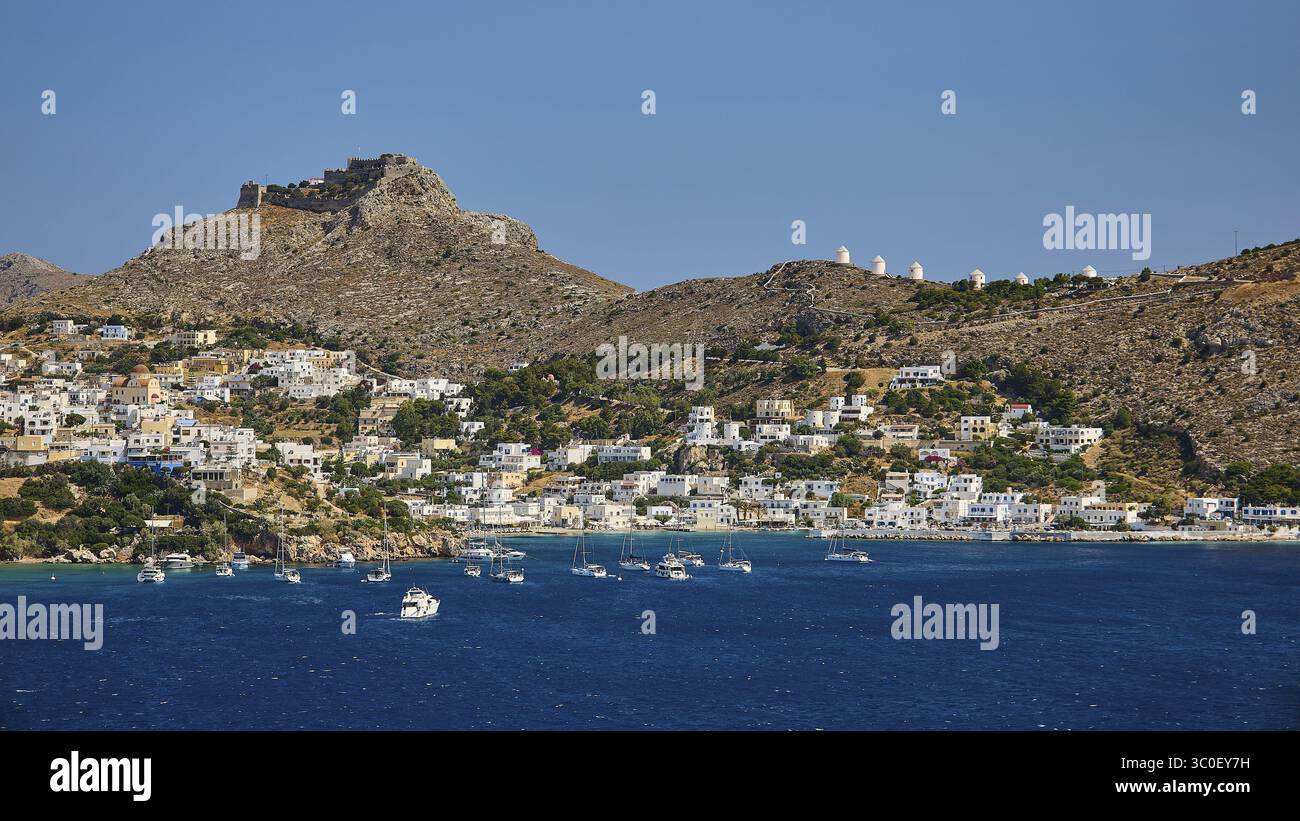 Küstenstadt auf einem blauen Meer mit Hügel und Burg im Hintergrund, gesäumt von Segelbooten, Pandeli Castle, Schloss, Leros Festung, St. John's Fortres Stockfoto