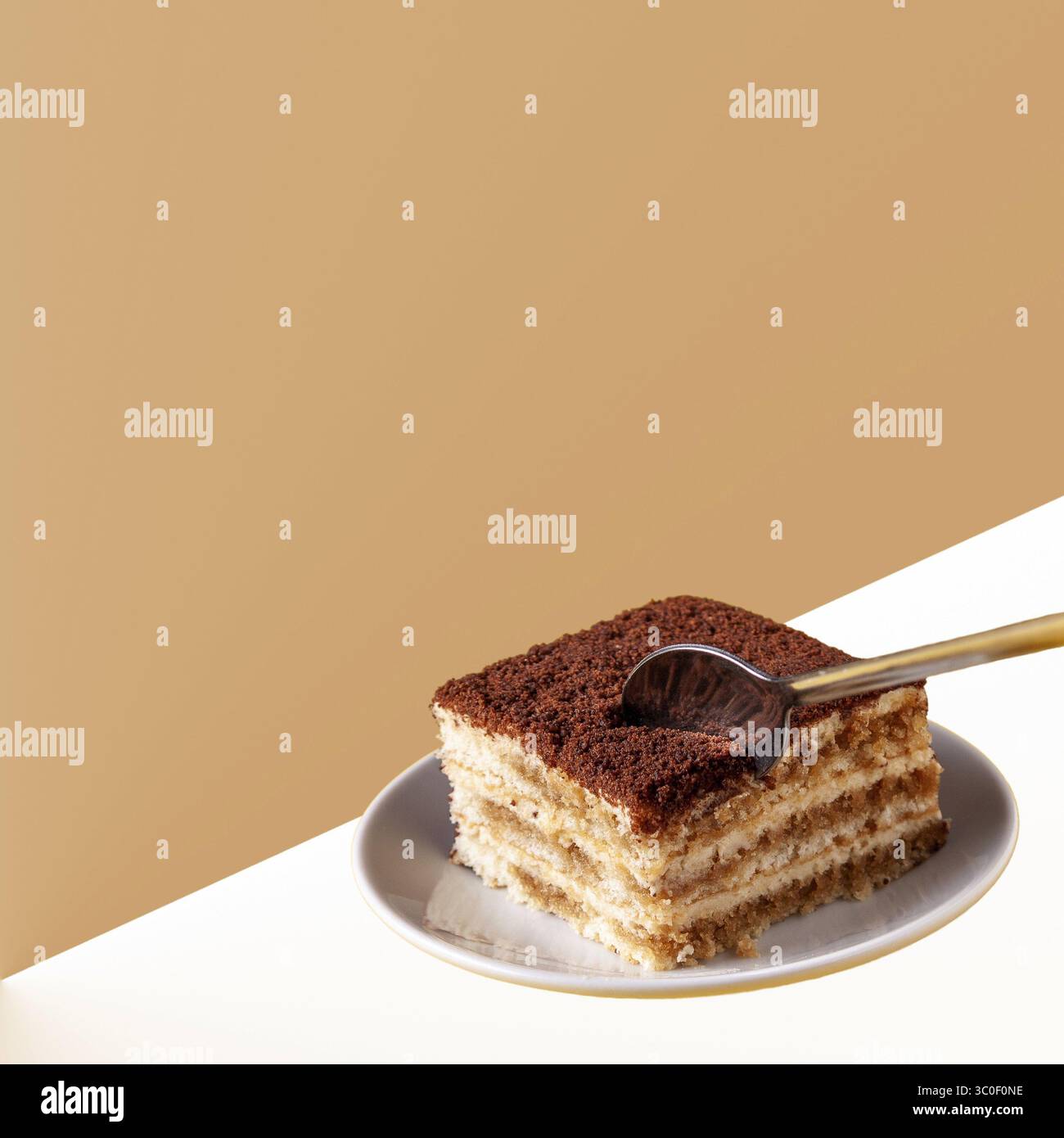 Löffel bricht ein Stück Tiramisu ab, das auf einem Teller liegt, Kopierraum Stockfoto