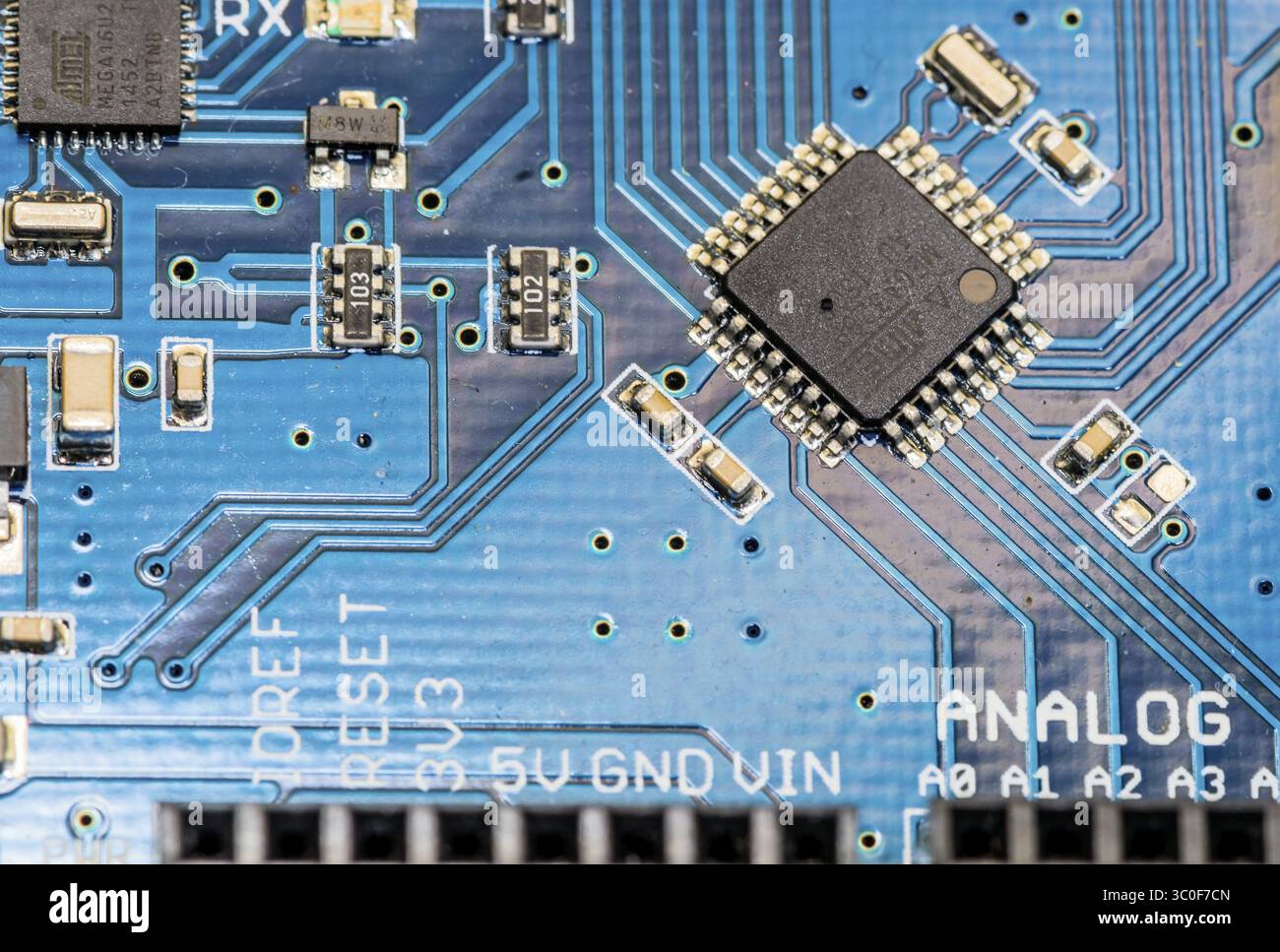 Detailansicht eines Mikrochips auf einer blauen Leiterplatte mit elektronischen Komponenten Stockfoto