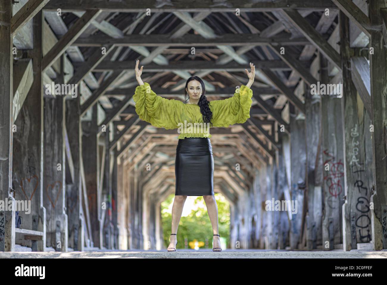 Frau in gelber Bluse und schwarzem Rock posiert mit erhobenen Armen auf einer Brücke, Fashion Shooting, Auguetbruecke, Muri, Bern, Kanton Bern, Schweiz Stockfoto