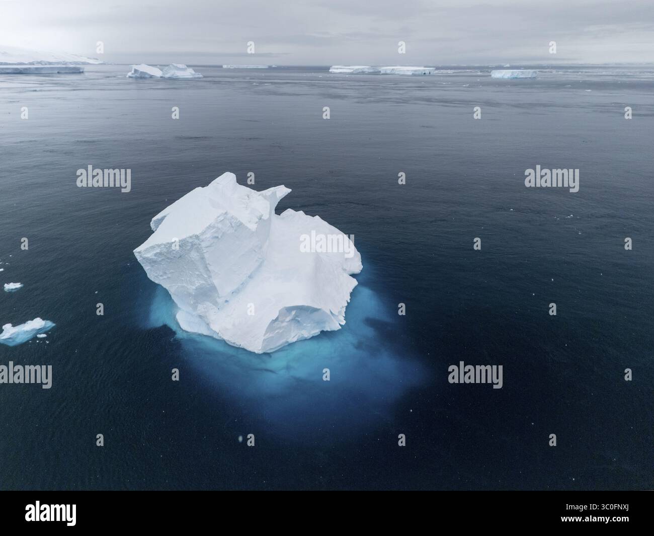 Aus der Vogelperspektive eines scharf weißen Eisbergs, der auf dem tiefblauen antarktischen Wasser schwimmt, ein Kontrast von eisiger Brillanz gegen das düstere Meer, Seymour Island, Antarktis. Stockfoto