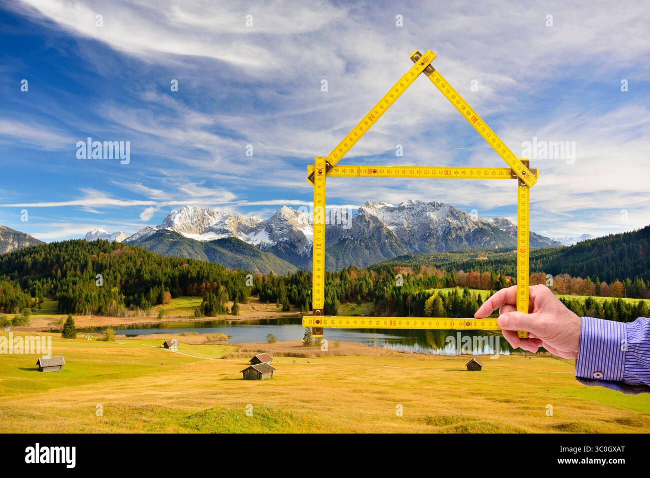 Wohnen auf dem Land, Handschuh in der Natur ein Meterstab ist gefaltet wie ein Haus und wird mit der Hand vor einer unberührte Landschaft, Handschuh in der N Stockfoto