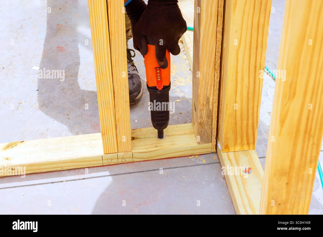 Der Handwerker installiert während der Arbeit tagsüber mit einer Druckluftpistole in gut beleuchteter Werkstattumgebung einen Holzrahmen. Stockfoto