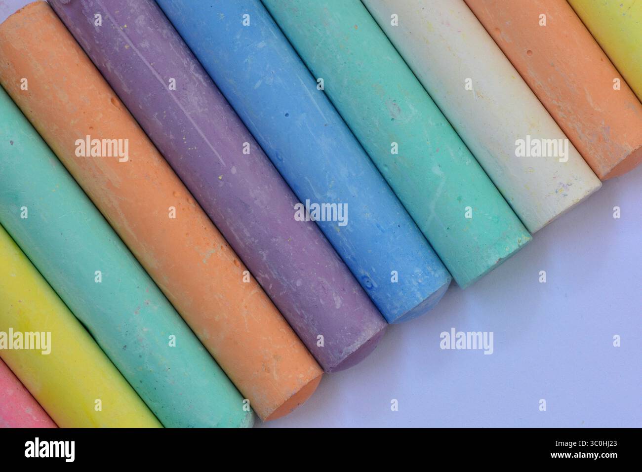 Nahaufnahme pastellfarbener Kreidestäbchen in diagonaler Anordnung. Künstlerische Textur und Farbvielfalt geeignet für Bildung, Kreativität oder Stockfoto