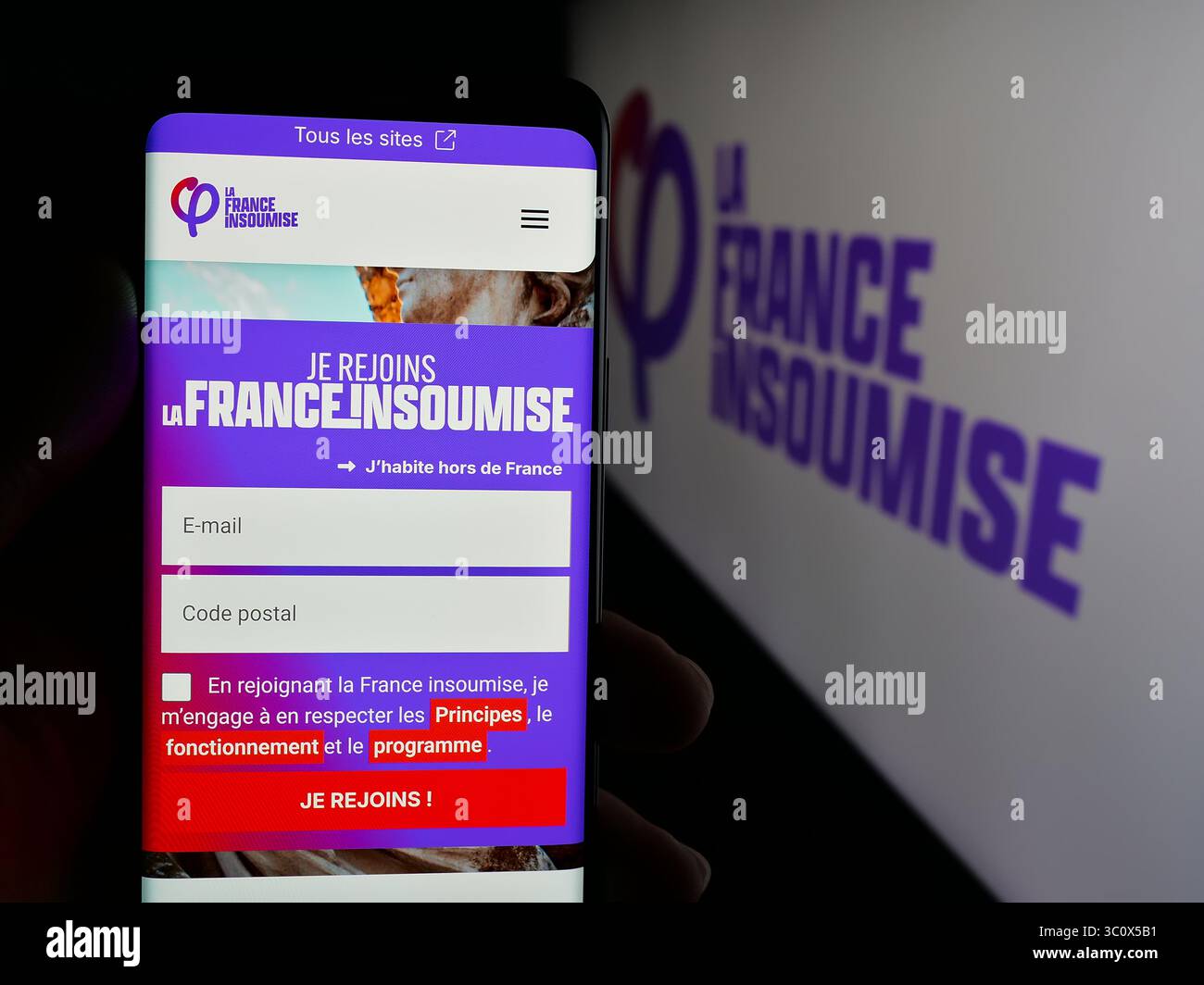 In dieser Abbildung hält eine Person ein Smartphone mit der Webseite der französischen Partei La France Insoumise (FI) auf dem Bildschirm vor dem Logo. Stockfoto