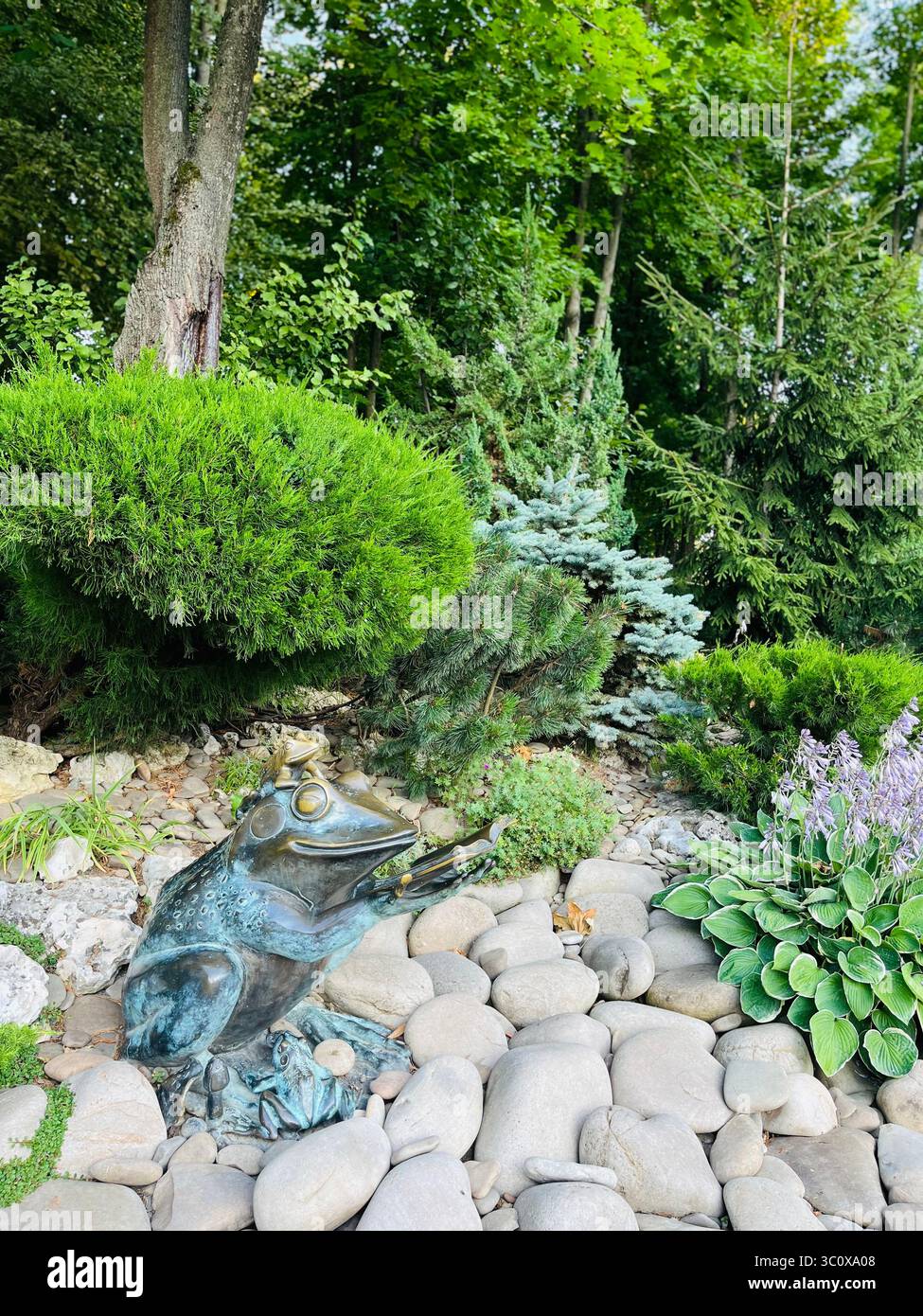 Stadtparkbrunnen umgeben von üppig grünen Bäumen, mit ruhigem Teichwasser, das die Sommerlandschaft widerspiegelt. Urbanes Natur- und Freizeitkonzept. Stockfoto