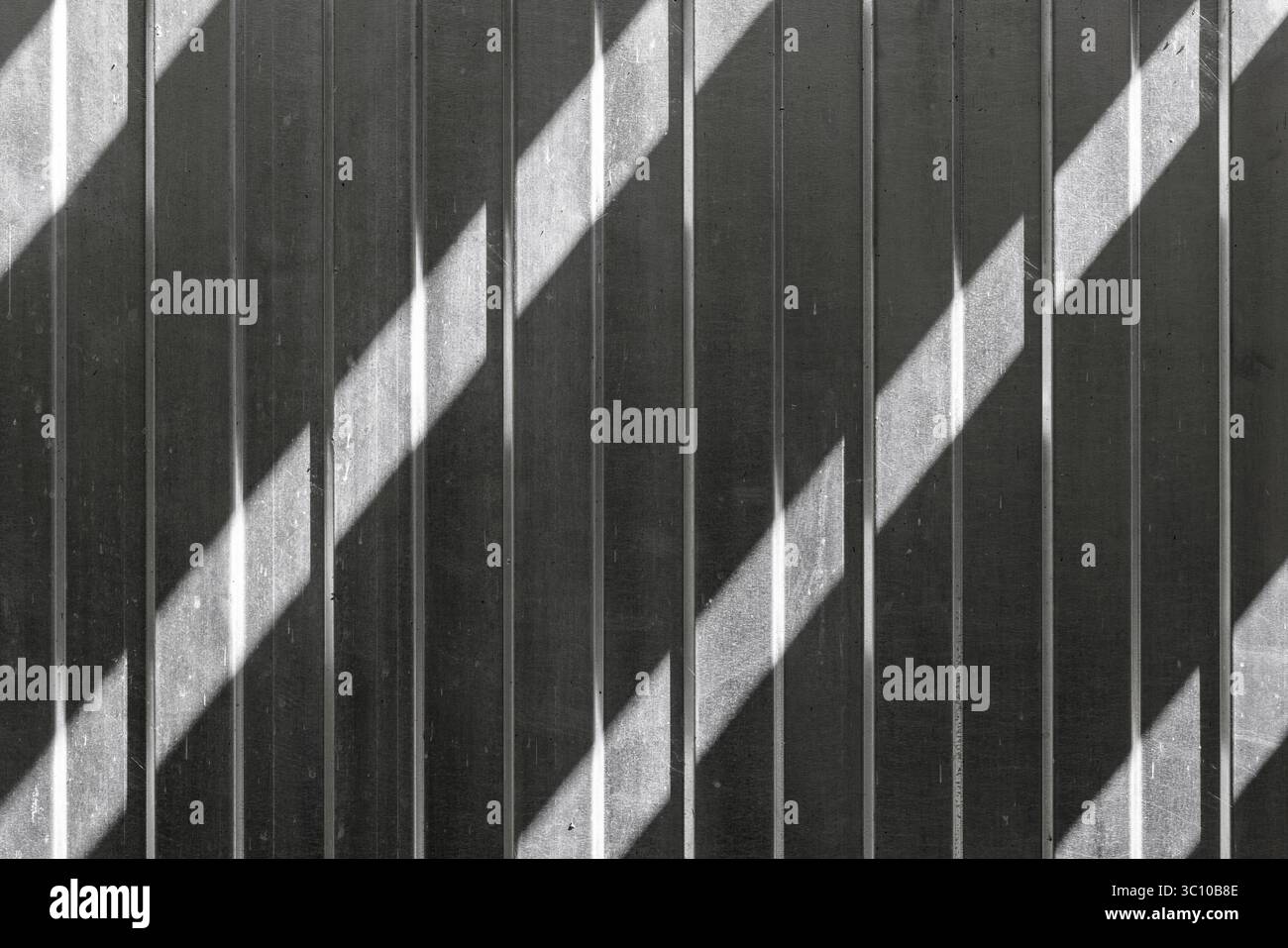 Geometrische Schatten erzeugen eine diagonale Brille auf einem strukturierten metallischen Hintergrund. Die minimalistische monochrome Komposition unterstreicht das Zusammenspiel von Stockfoto