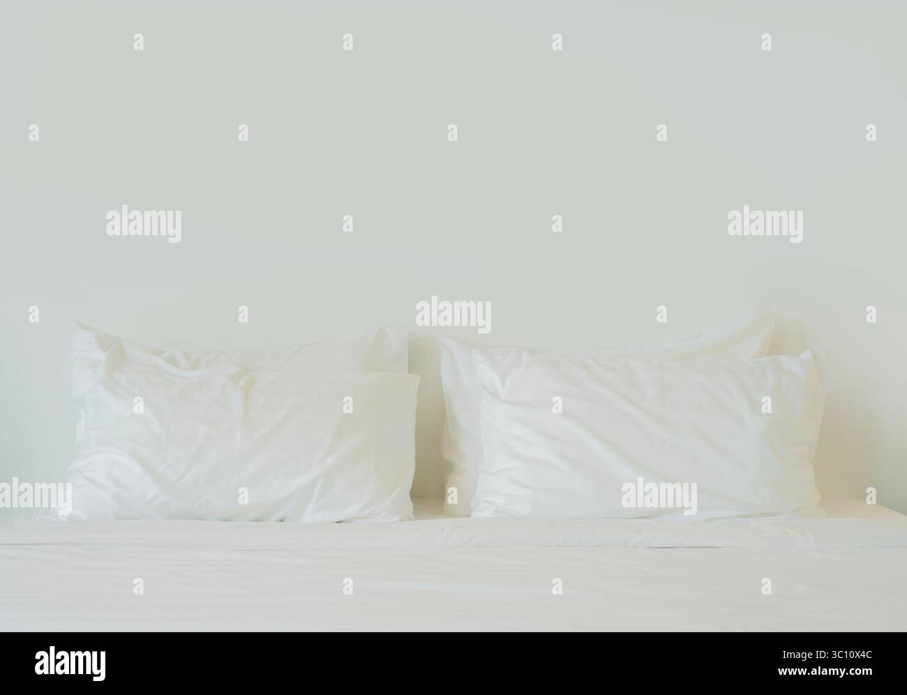 Bequeme weiche Kissen auf dem Bett. Weiße Bettwäsche und Kissen in Nahaufnahme auf hellem Hintergrund. Kopierbereich. Stockfoto