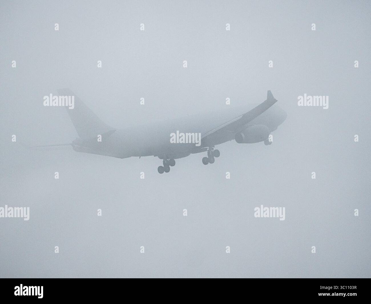 Ein Tankflugzeug der Royal Netherlands Air Force landet während einer NATO-Übung in dickem Nebel, dessen Silhouette durch den Nebel kaum sichtbar ist. Stockfoto