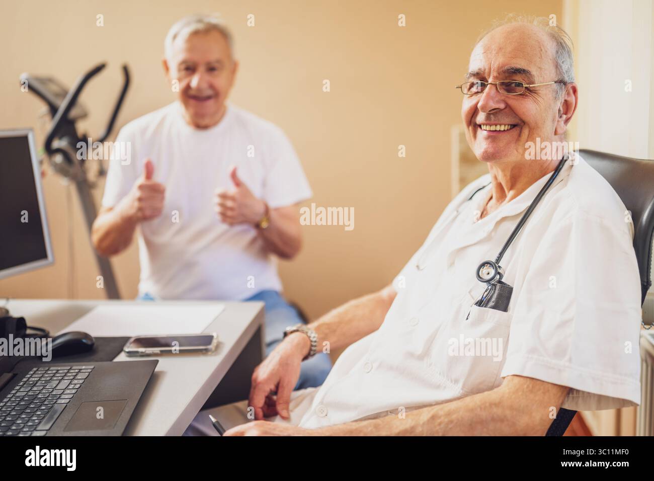Glücklicher Patient mit ärztlicher Untersuchung beim Kardiologen. Zufriedener Arzt und Patient, der in die Kamera blickt und lächelt. Stockfoto