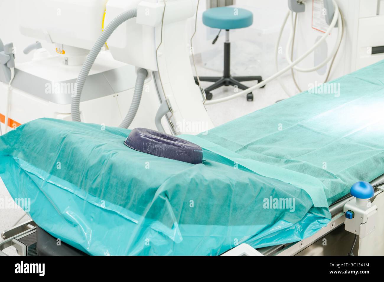 Ein OP-Raum wird für eine Operation vorbereitet, mit einem medizinischen Tisch bedeckt mit sterilen Vorhängen und verschiedenen Geräten im Hintergrund. Stockfoto