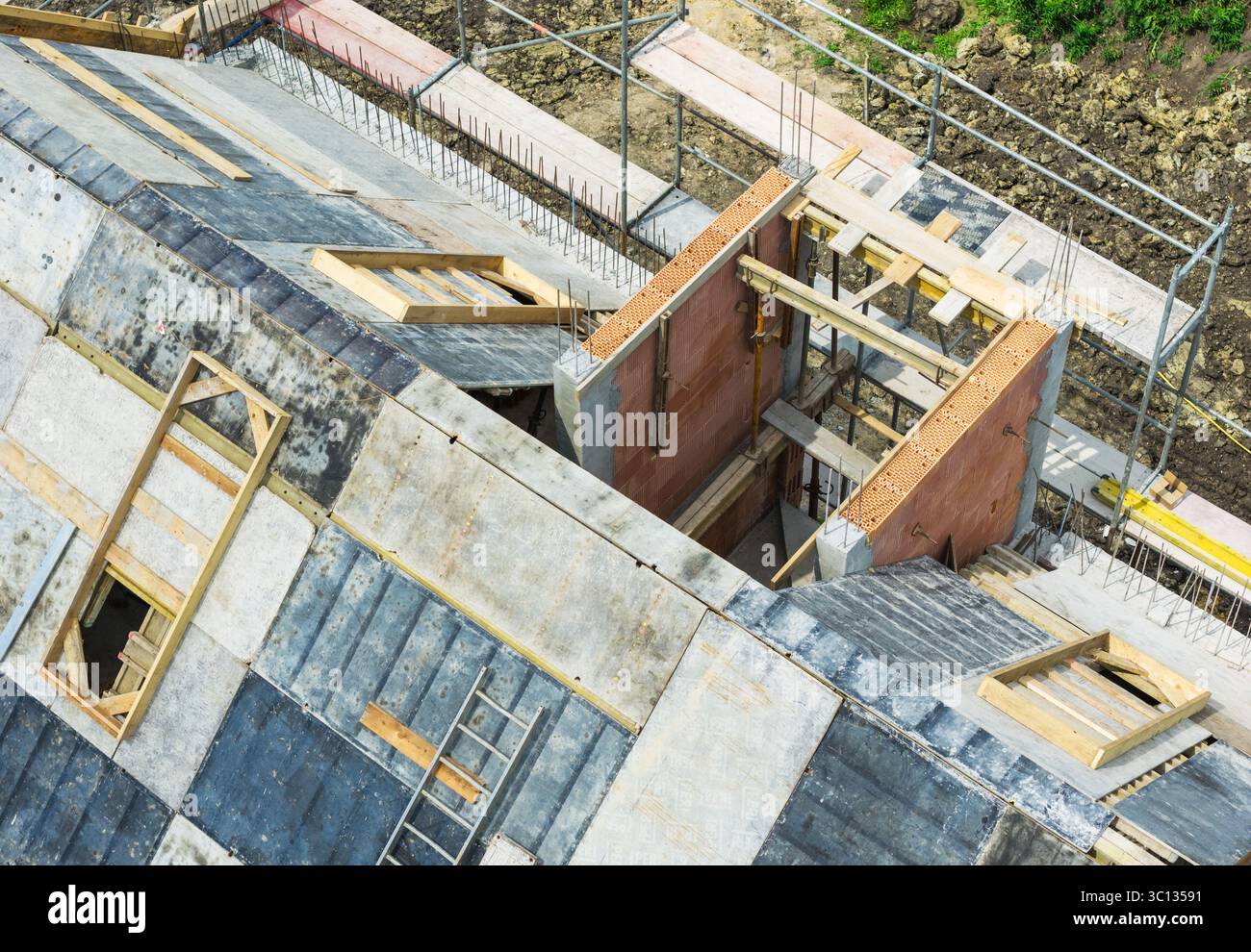 Ein modernes Gebäude im Bau zeigt sein Gerüst und Gerüst an ländlicher Lage. Die Arbeiter sind an verschiedenen Bauaktivitäten beteiligt Stockfoto