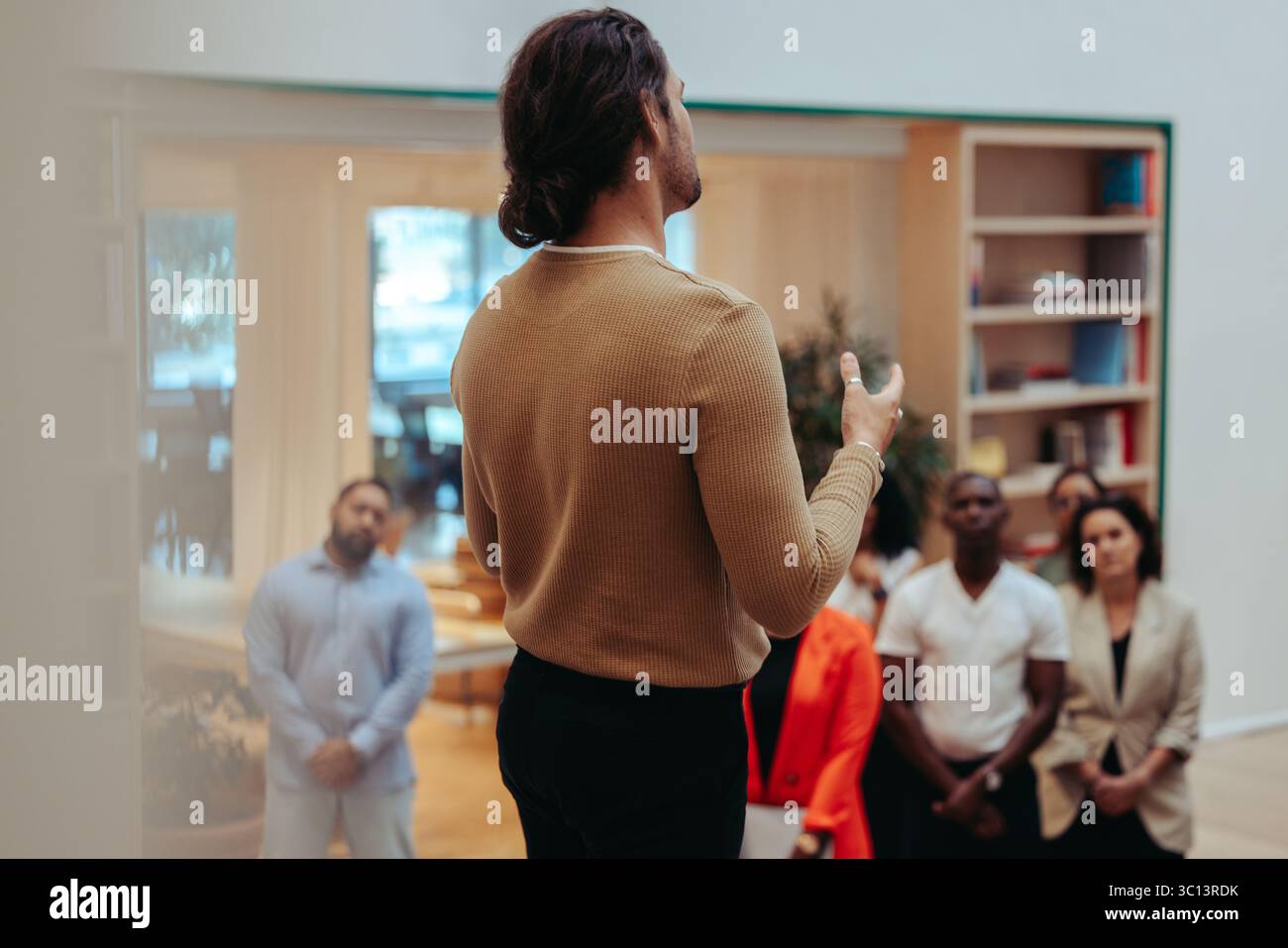 Ein professioneller Redner leitet ein informelles Treffen, bei dem es um die Vermittlung von Startup-Prinzipien geht. Die moderne Büroumgebung und das aufmerksame Publikum werden erfasst Stockfoto