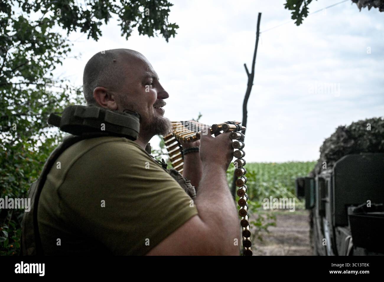 Ein Soldat eines mobilen Feuerwehrteams der 31. Mechanisierten Brigade der Ukraine hält einen Maschinengewehrgürtel, während er am 11. Juli 2025 in der Richtung Zaporischschhia in der Ukraine unterwegs ist. (Foto: Dmytro Smolienko/Ukrinform) Stockfoto