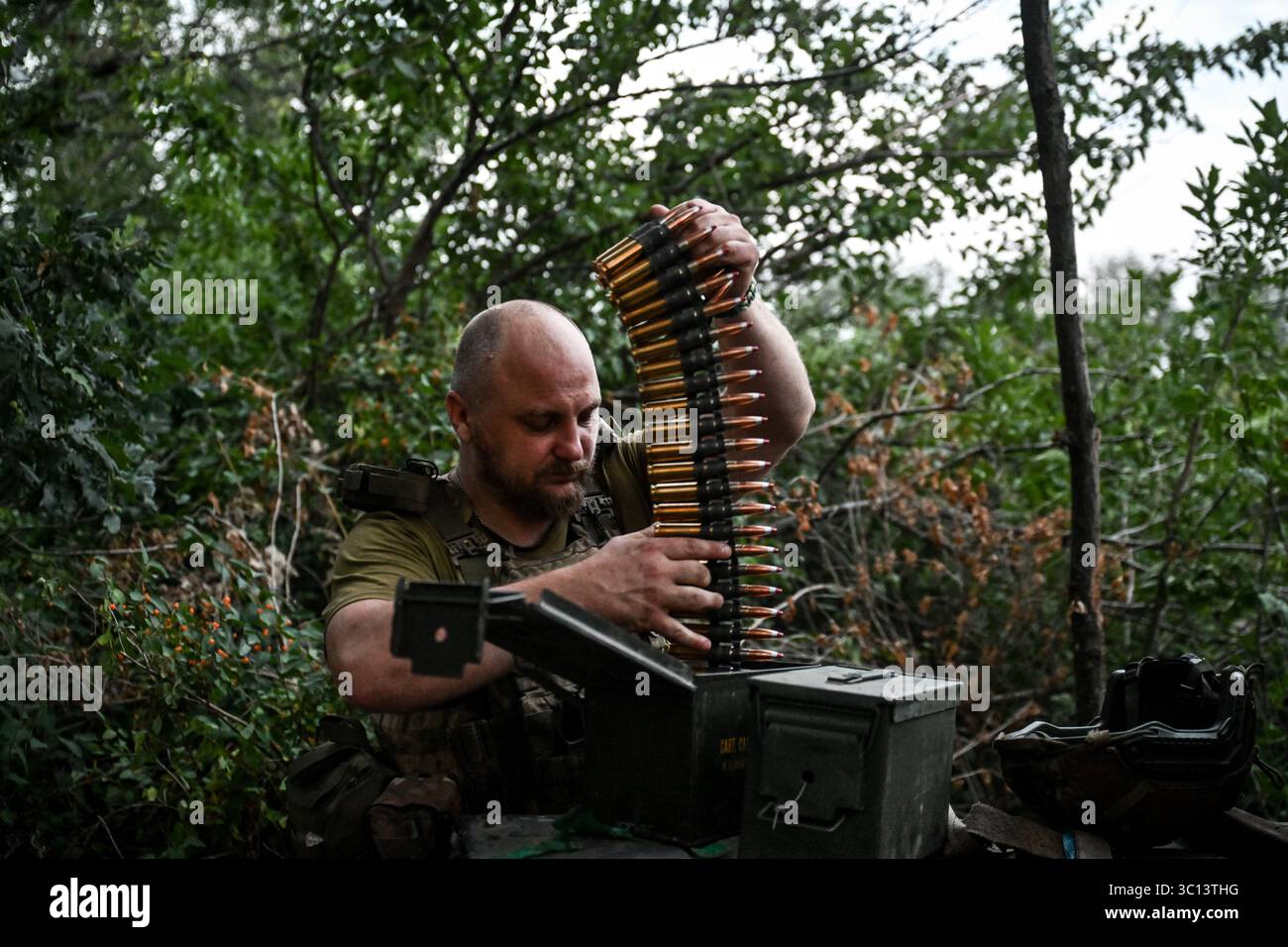 Ein Soldat eines mobilen Feuerwehrteams der 31. Mechanisierten Brigade der Ukraine hält einen Maschinengewehrgürtel, während er am 11. Juli 2025 in der Richtung Zaporischschhia in der Ukraine unterwegs ist. (Foto: Dmytro Smolienko/Ukrinform) Stockfoto
