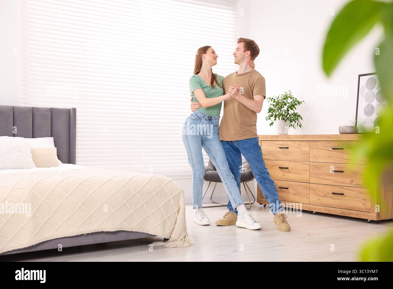 Glückliches junges Paar, das im Schlafzimmer zusammen tanzt Stockfoto