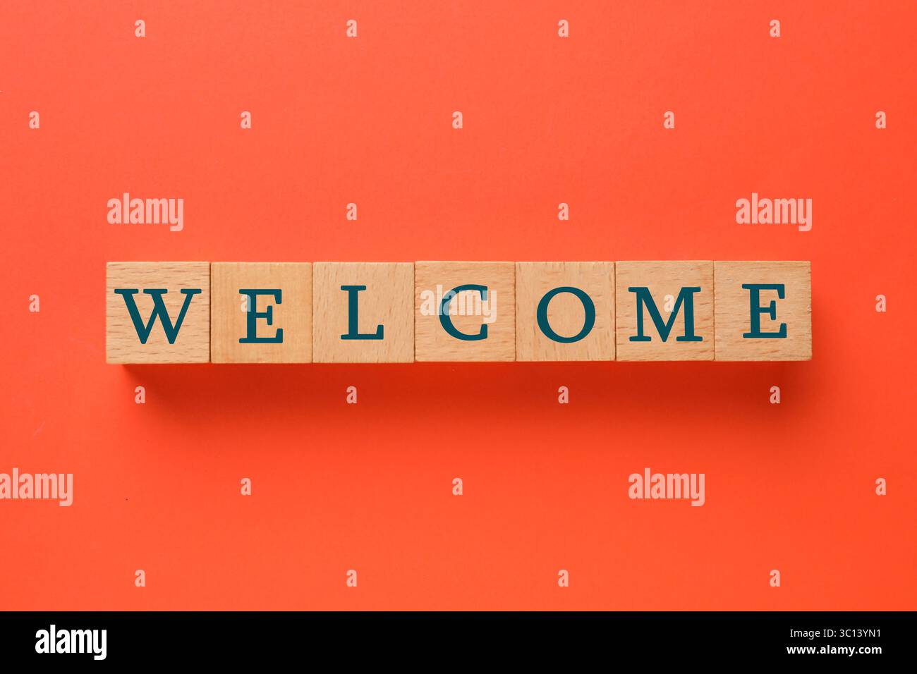 Word Welcome aus Holzwürfeln auf rotem Hintergrund, Blick von oben Stockfoto