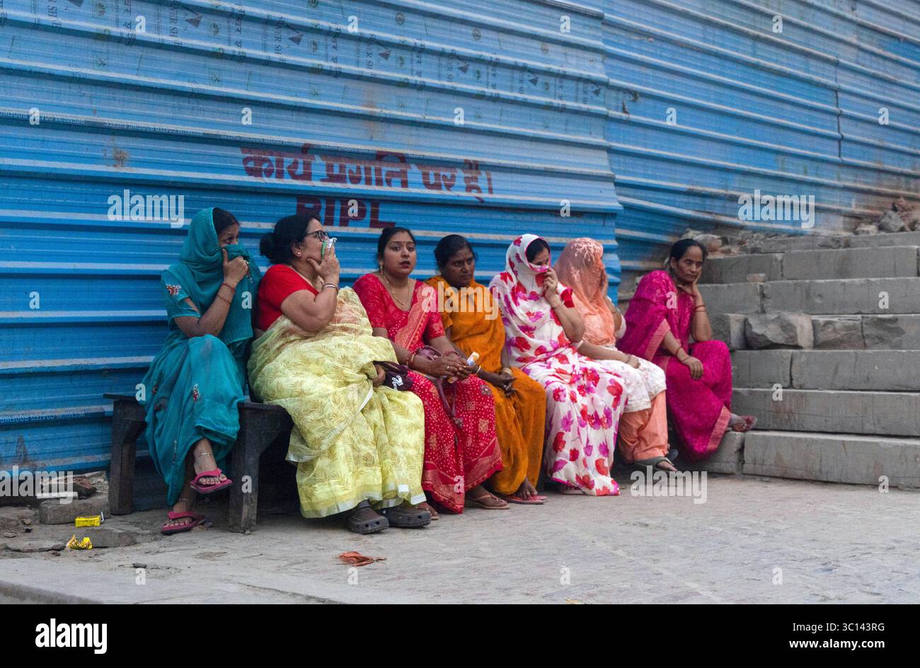 Begräbnistraditionen und Verschmutzung in Manikarnika Ghat, in Indien, sitzt Eine Gruppe von Frauen mit einigen von ihnen, die ihre Gesichter bedecken, in der Nähe einer Einäscherungsstelle in Harishchandra Ghat in der Nähe des Manikarnika Ghat in Varanasi, Indien, am 7. Juni 2025. Manikarnika Ghat in Varanasi ist der heiligste Einäscherungsgrund des Hinduismus, ein ergreifendes Tor zur Befreiung. Sie glauben, dass sie Moksha-Rettung direkt gewähren, und unzählige Gläubige bringen ihre Verstorbenen hierher, um sich aus dem Zyklus der Wiedergeburt zu befreien. Diese tiefgreifende spirituelle Praxis hat jedoch eine hohe Umweltbelastung. Die kontinuierlichen Scheiterhaufen verbrauchen eine enorme Menge Stockfoto