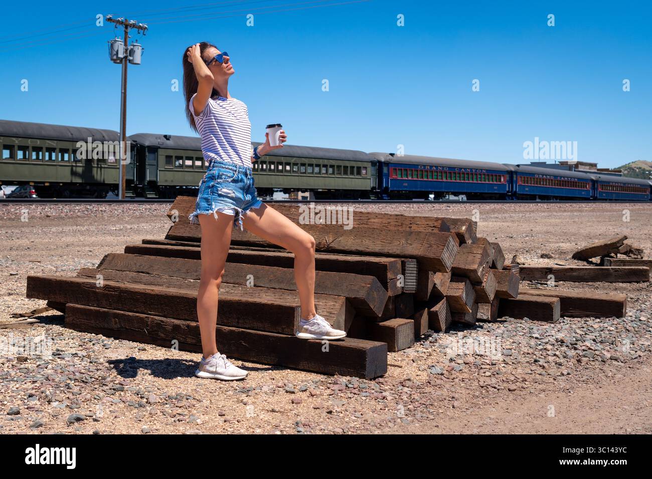 Junge kaukasische Frau mit Kaffee an verlassenen Bahngleisen Stockfoto