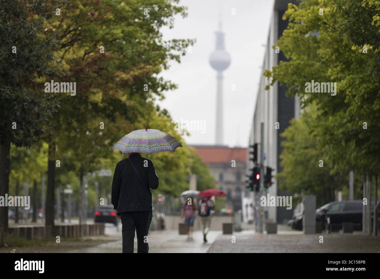 Menschen laufen mit Sonnenschirmen durch den Regierungsbezirk in Berlin, 21.07.2025 Stockfoto