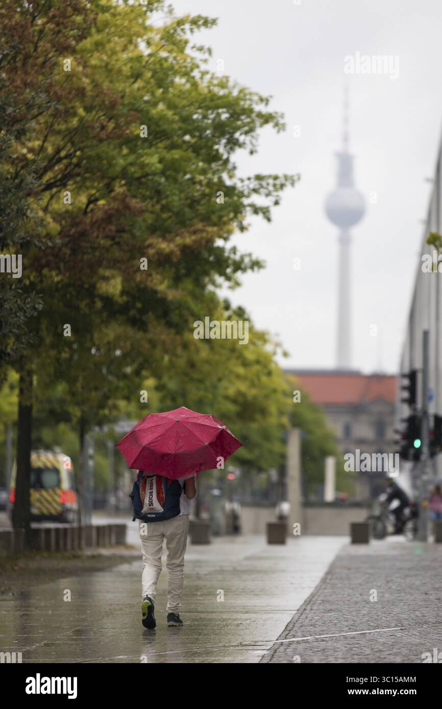 Menschen laufen mit Sonnenschirmen durch den Regierungsbezirk in Berlin, 21.07.2025 Stockfoto