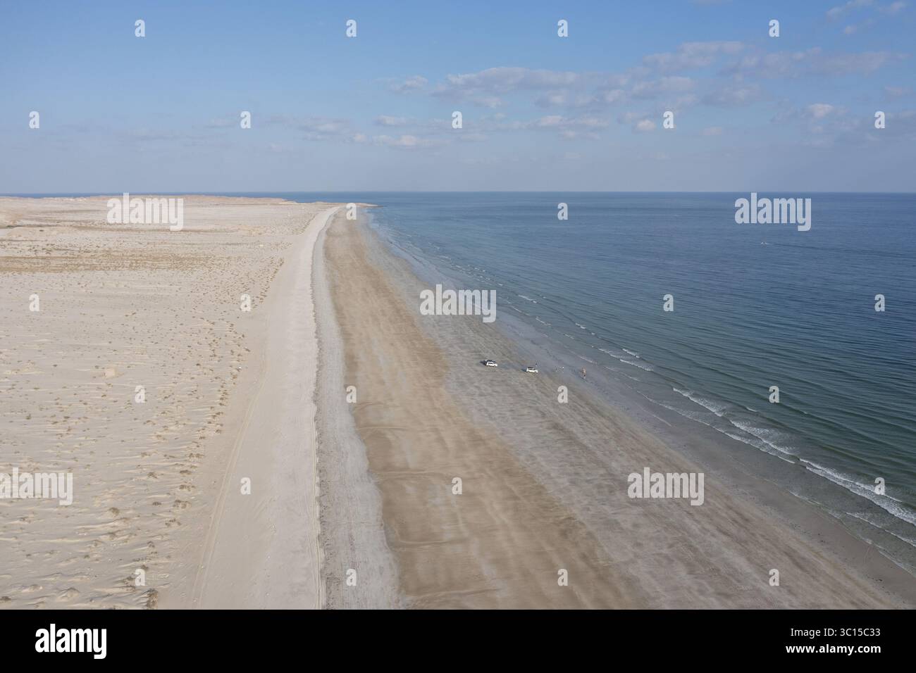 Blick aus der Vogelperspektive auf den endlosen Strand, wo der Wüstensand auf das ruhige türkisfarbene Wasser des Golfs von Oman, Maskat, Maskat Governorate, Oman trifft. Stockfoto